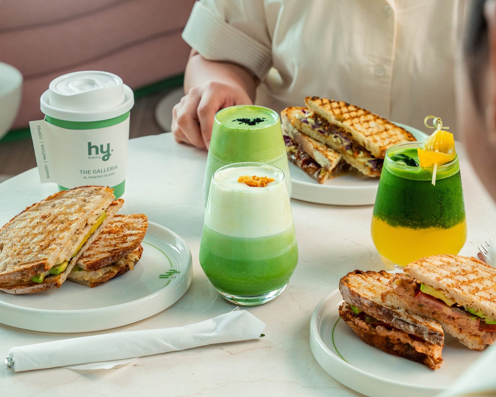 A table filled with hy Bakery breakfast, sandwiches and matcha
