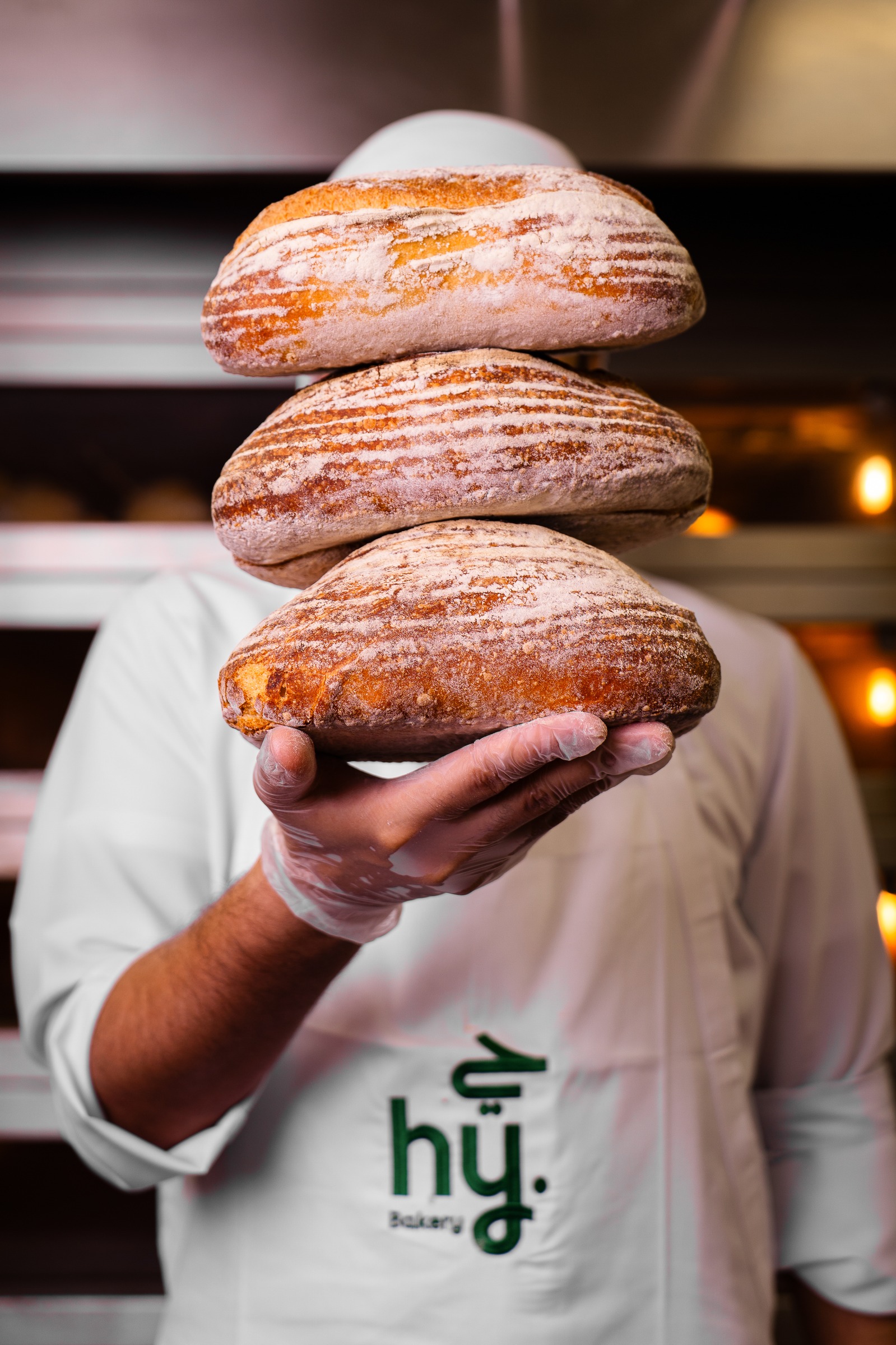 A hy Bakery baker holding three sourdough loaves